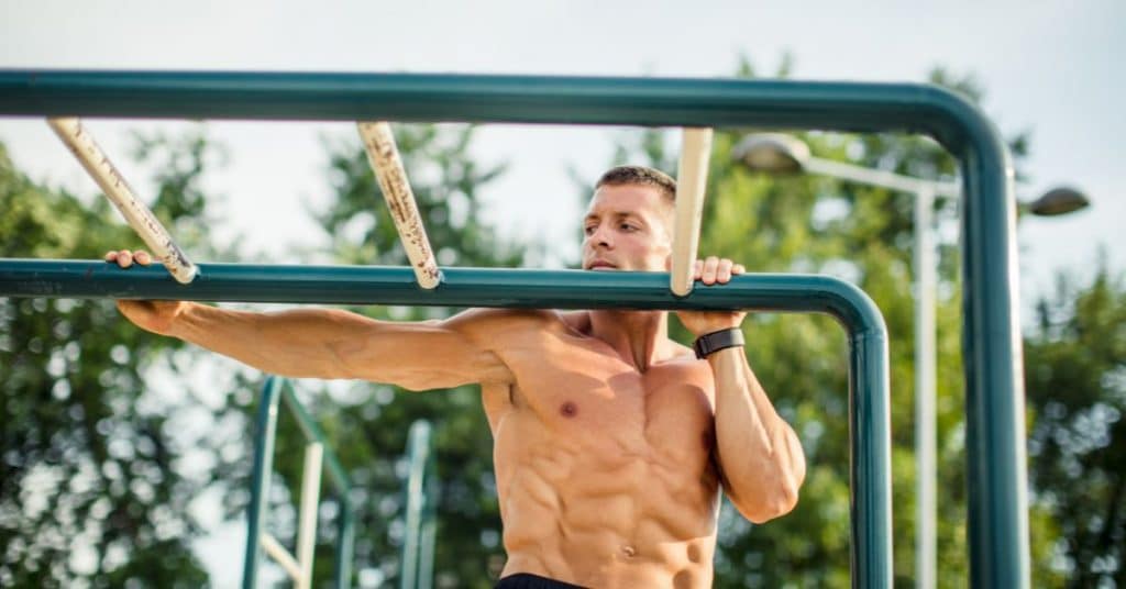 Strong man is doing an archer pull-up on a thick pull-up bar