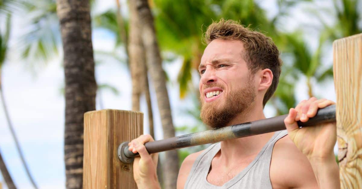Man with beard is doing a pull-up on an outdoor pull-up bar