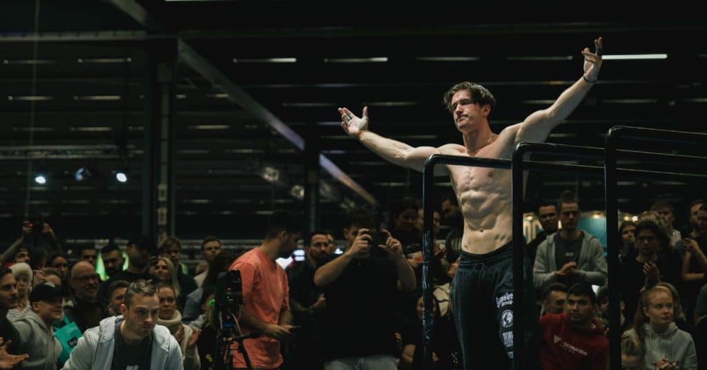This is the cover image for the 20 calisthenics competitions in 2024 blog including a picture of calisthenics athlete Simon Imhäuser at the Beast Of The Barz competition in Stockholm, Sweden.
